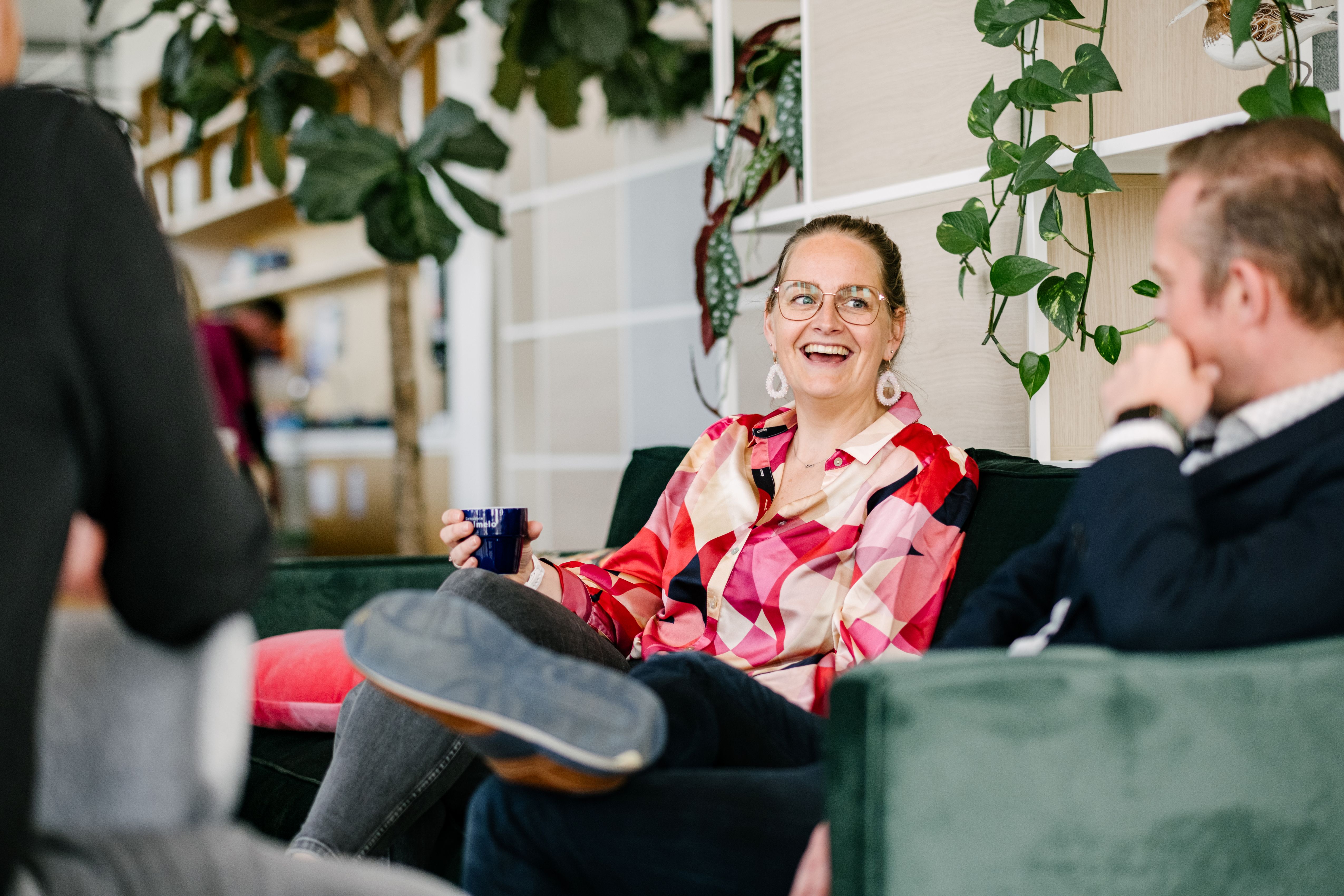 Een lachende vrouw met een kop koffie in de hand